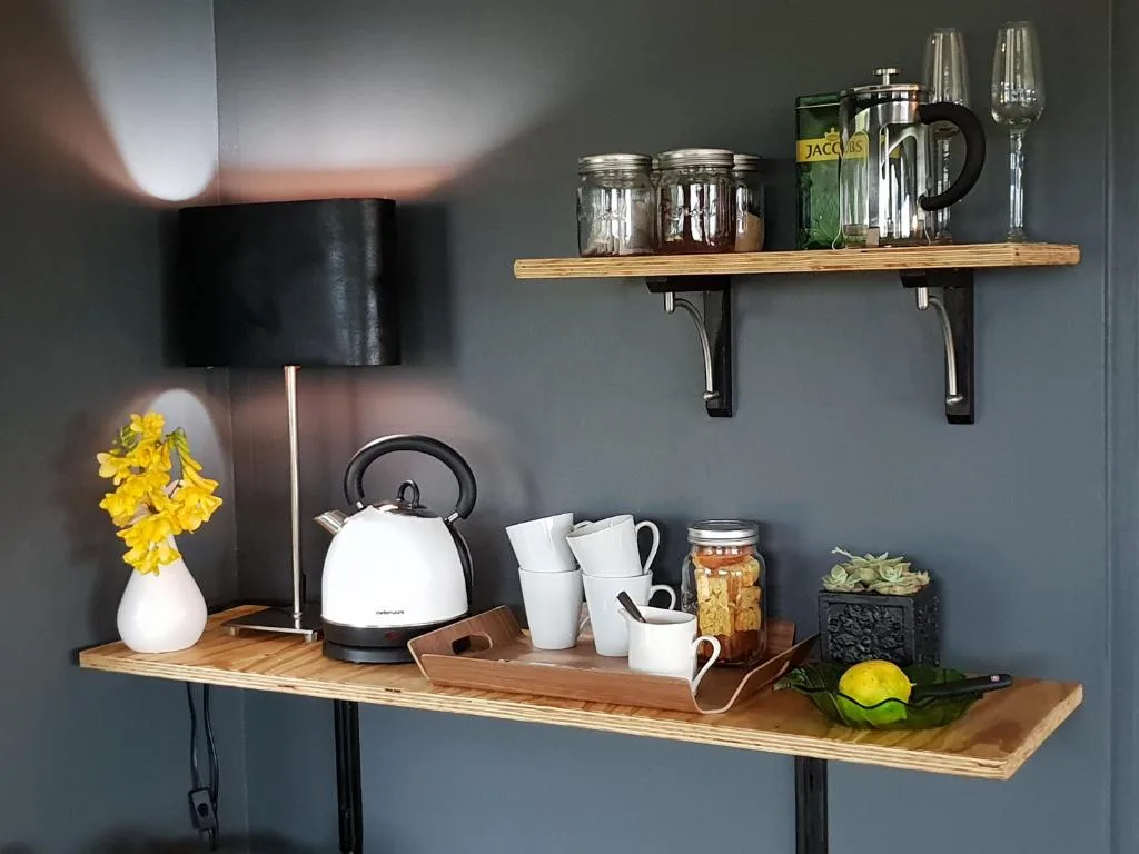Wooden shelves with kettle, mugs, glassware, and decorative accessories