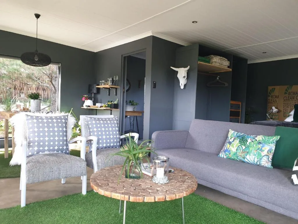 Spacious lounge with gray sofa, white chairs, wooden coffee table, and garden view