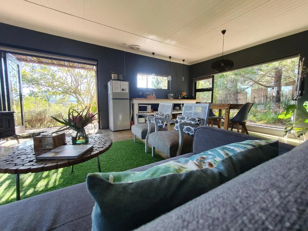 Open-plan living area with sofas, kitchenette, and garden views through large windows