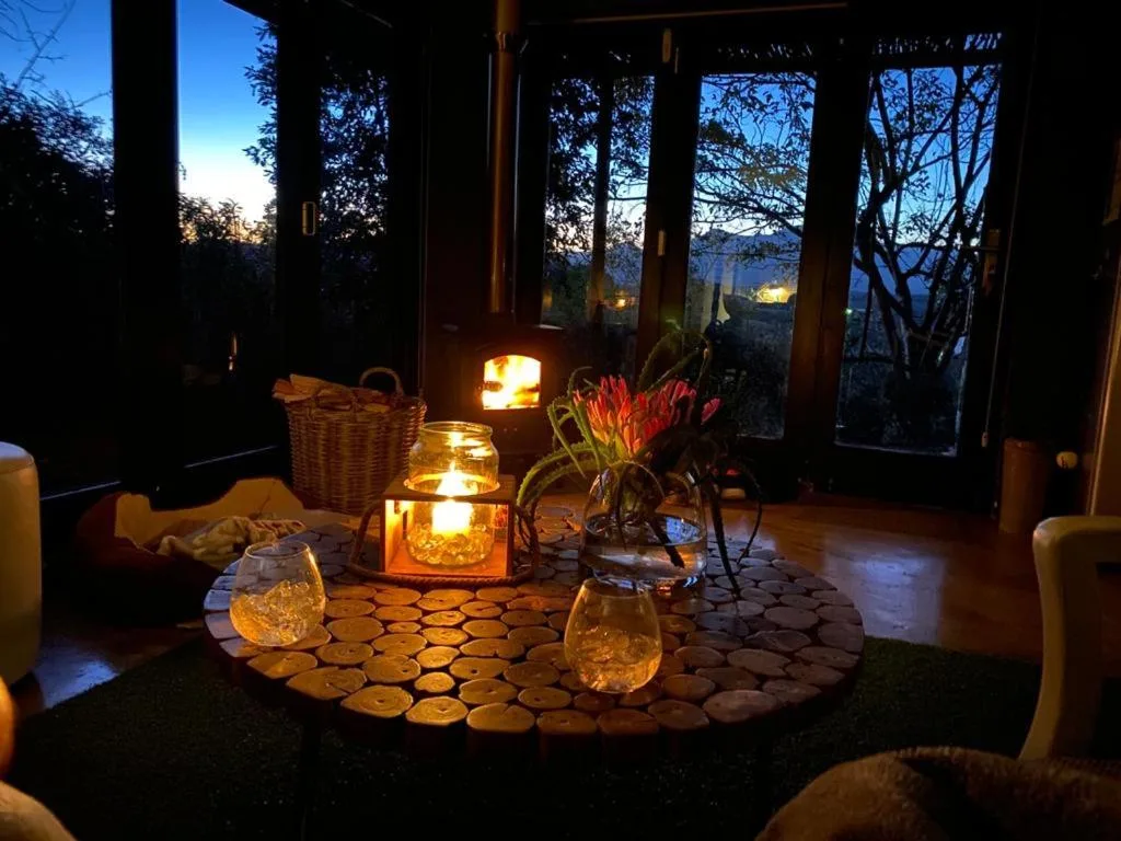 Cozy lounge interior with fireplace, candlelit table, and mountain views at dusk