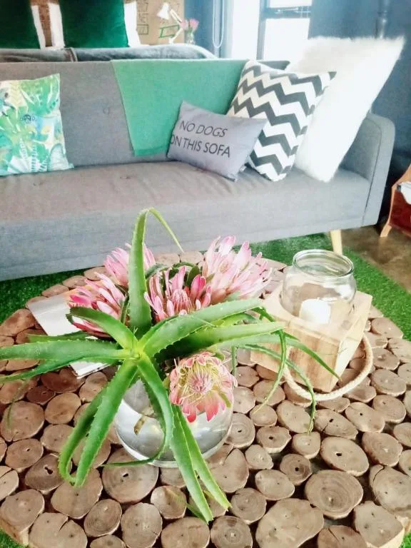 Modern grey sofa with colorful cushions and fresh pink proteas on wooden coffee table