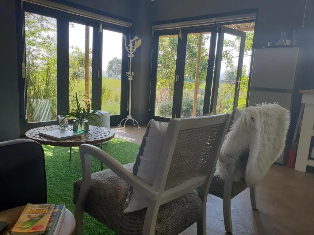 Modern lounge with seating, round table, green field views through large windows