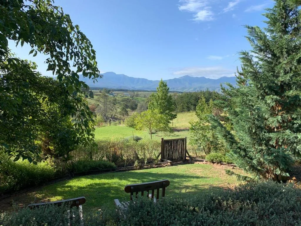 Mountain valley landscape with lush gardens and distant peaks visible