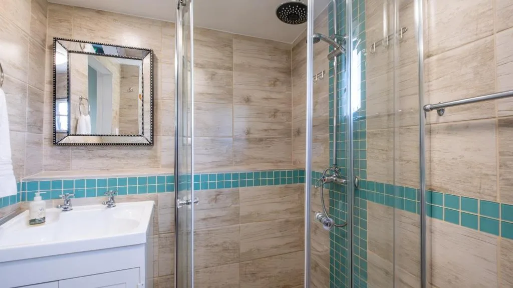 Modern bathroom with turquoise tile accents and walk-in shower enclosure