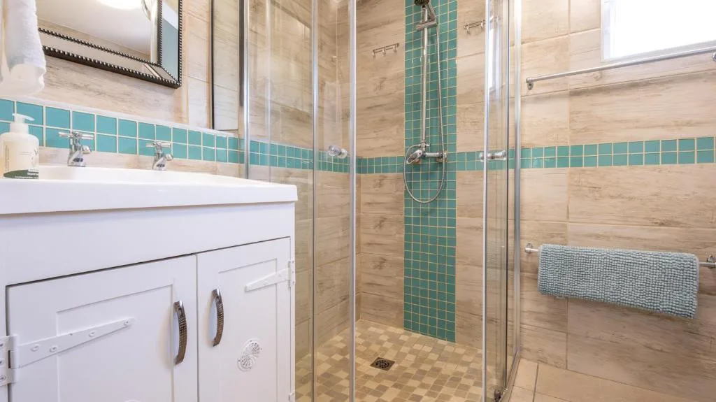 Modern bathroom with turquoise tile accents and glass shower enclosure