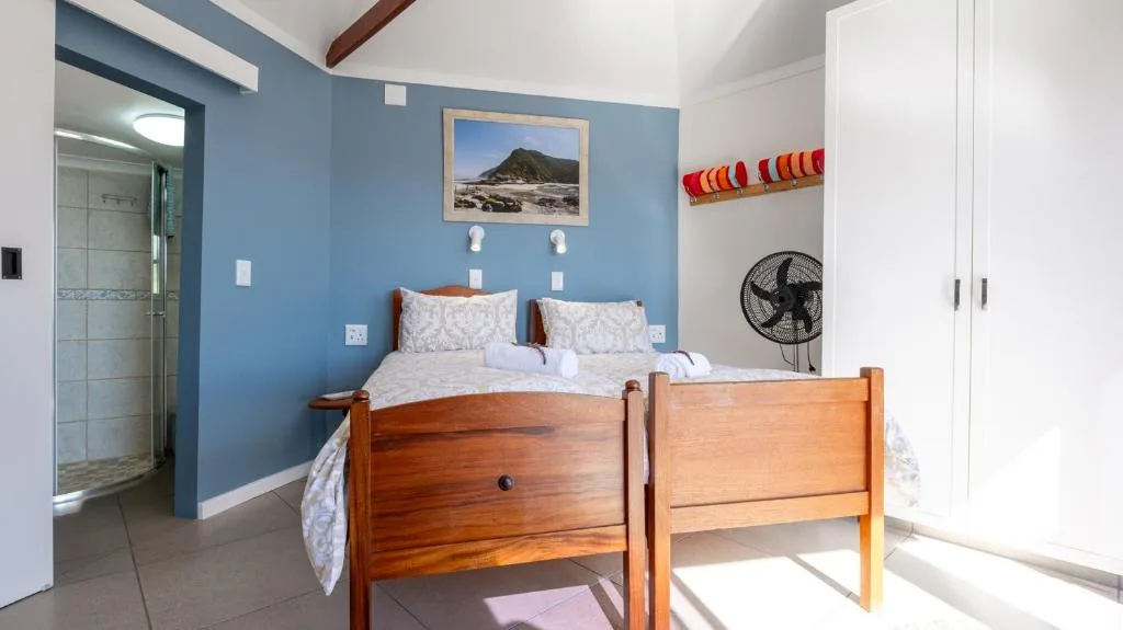 Bright bedroom with wooden bed frame and blue accent wall, ensuite bathroom visible