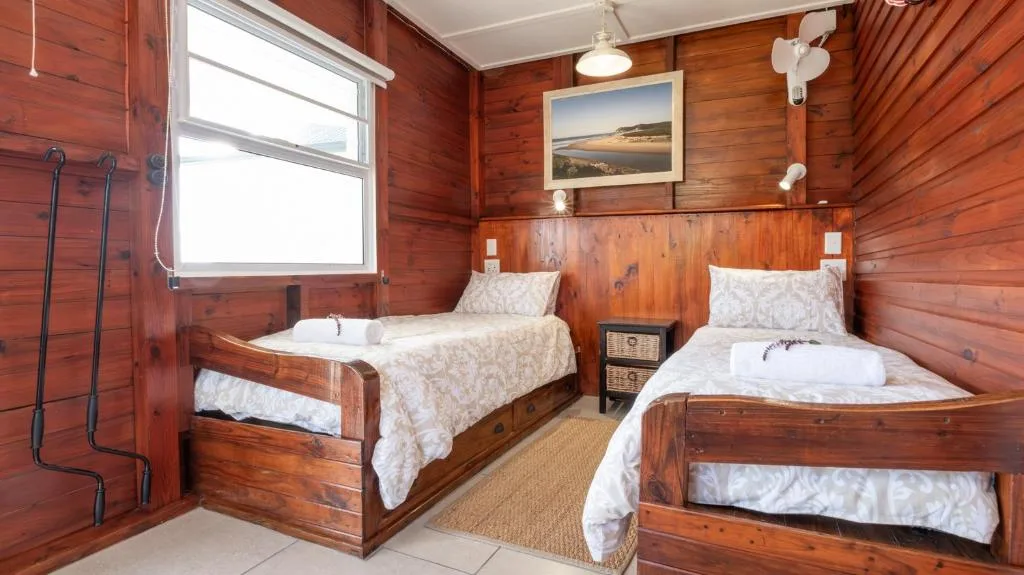 Twin wooden beds in warmly-lit cottage bedroom with natural light
