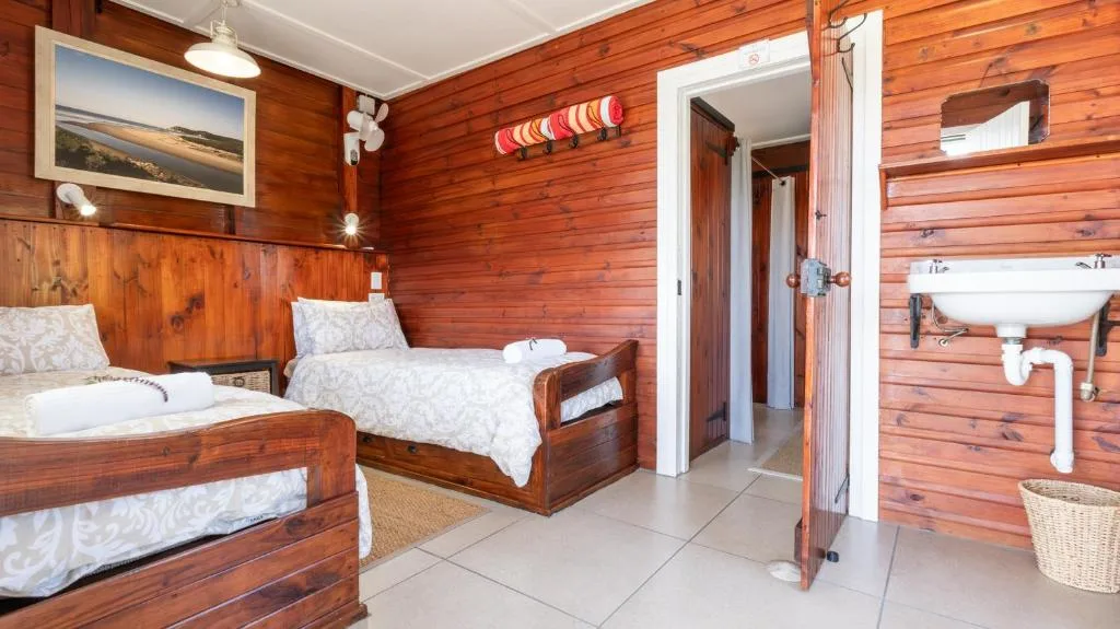Wooden cabin bedroom with two beds and ensuite bathroom visible