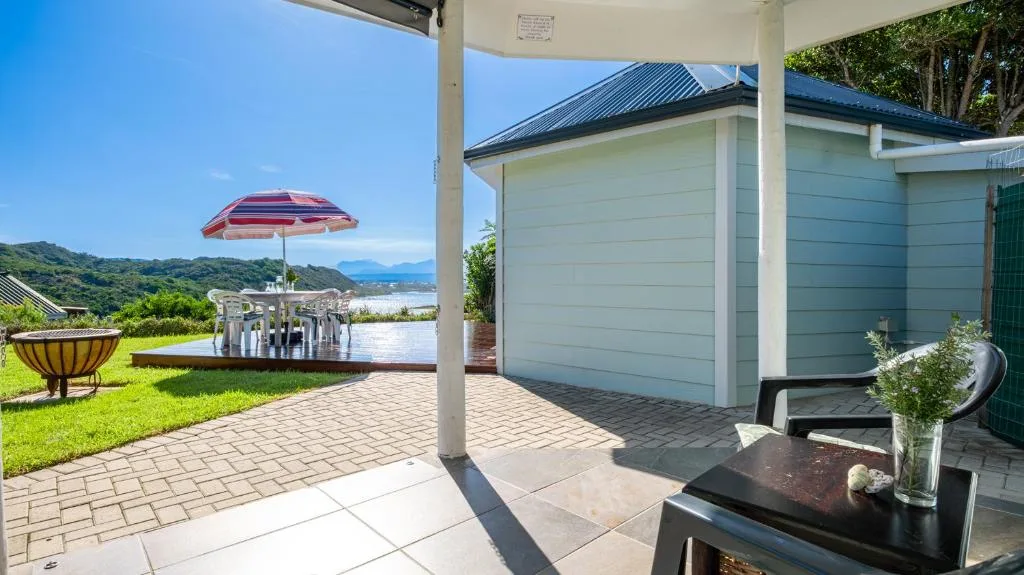Covered patio with lagoon and mountain views, red umbrella, outdoor seating