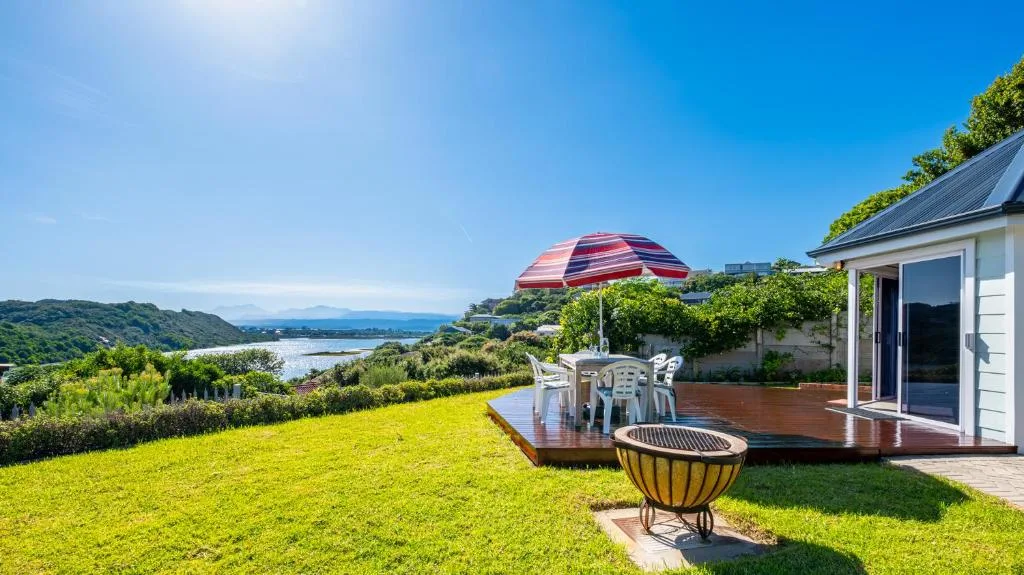Wooden deck with umbrella and seating overlooking lagoon and hills