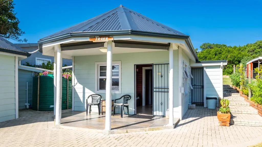 Charming white cottage with peaked metal roof and covered porch area