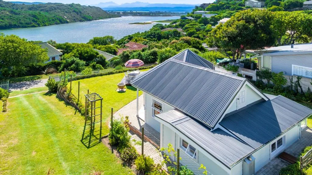 Modern cottage with metal roof overlooking lagoon and lush gardens