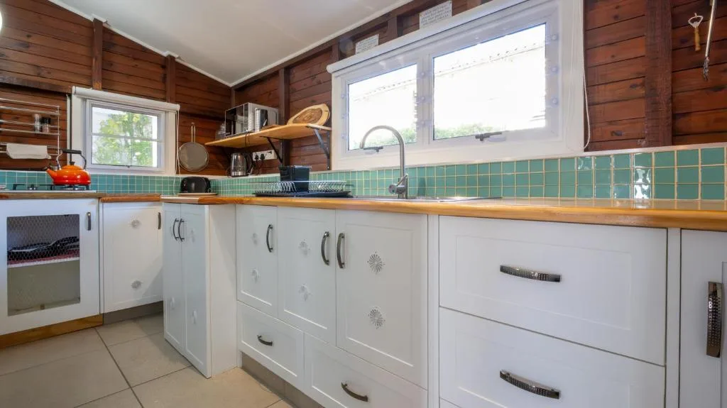 Modern kitchen with white cabinetry, turquoise tile backsplash, wooden walls