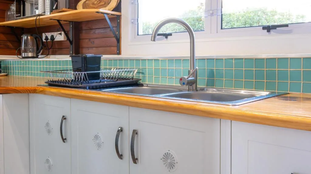 Modern kitchen with turquoise tile backsplash, wooden countertop, and stainless steel sink