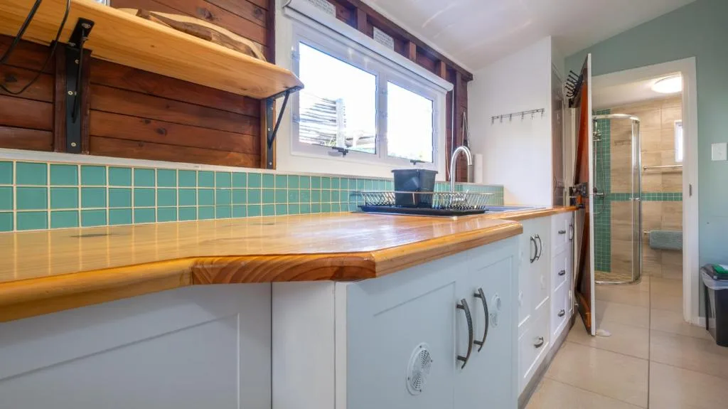 Modern kitchen with wooden countertop, turquoise tile backsplash, white cabinetry
