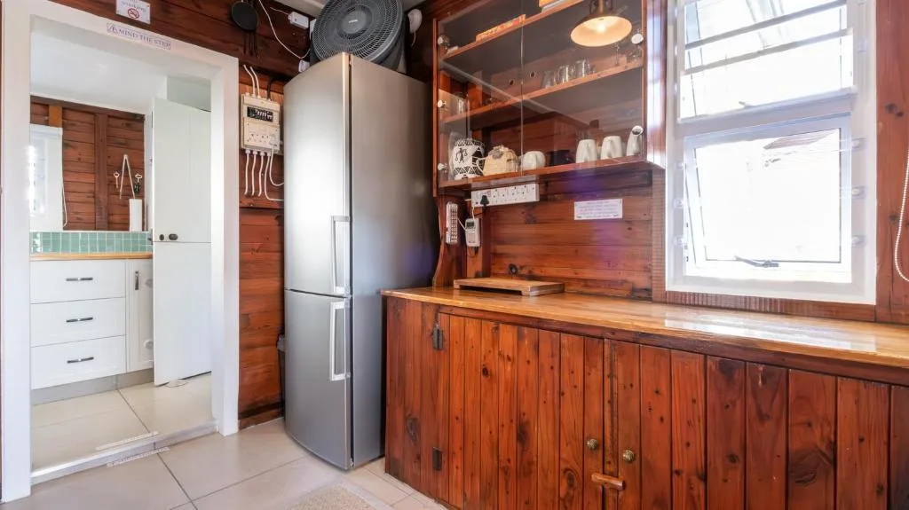 Modern kitchen with stainless steel fridge, wooden cabinetry, and bright windows