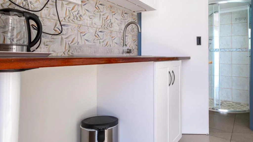 Modern kitchen with white cabinetry, wooden counter, and patterned backtile