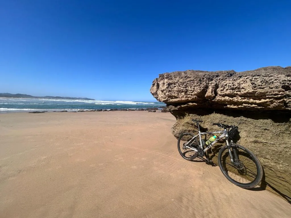 Scenic beach view with rocky outcrop and bicycle resting against stone