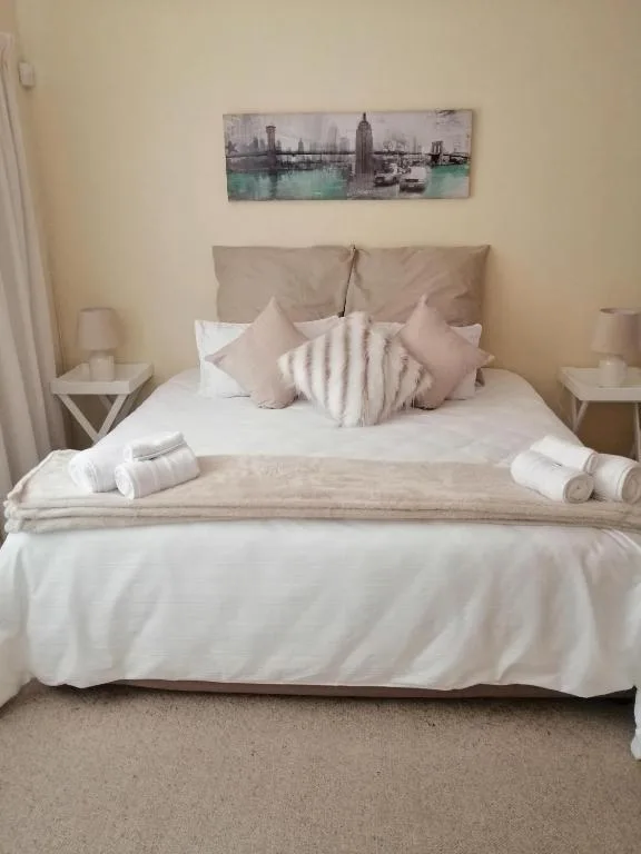 Neatly made bed with neutral pillows and white linens, bedside tables