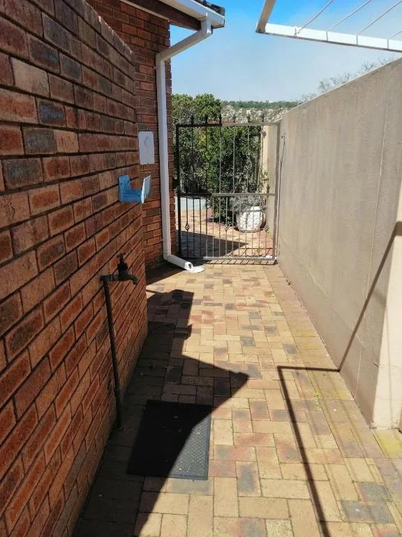 Sunny paved patio area with brick walls and garden views beyond