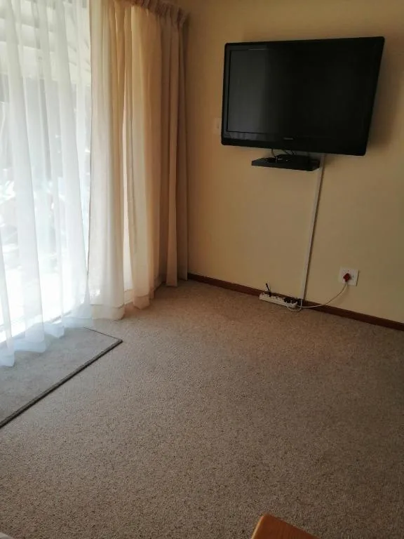 Living room with wall-mounted TV, window with curtains, and carpet flooring