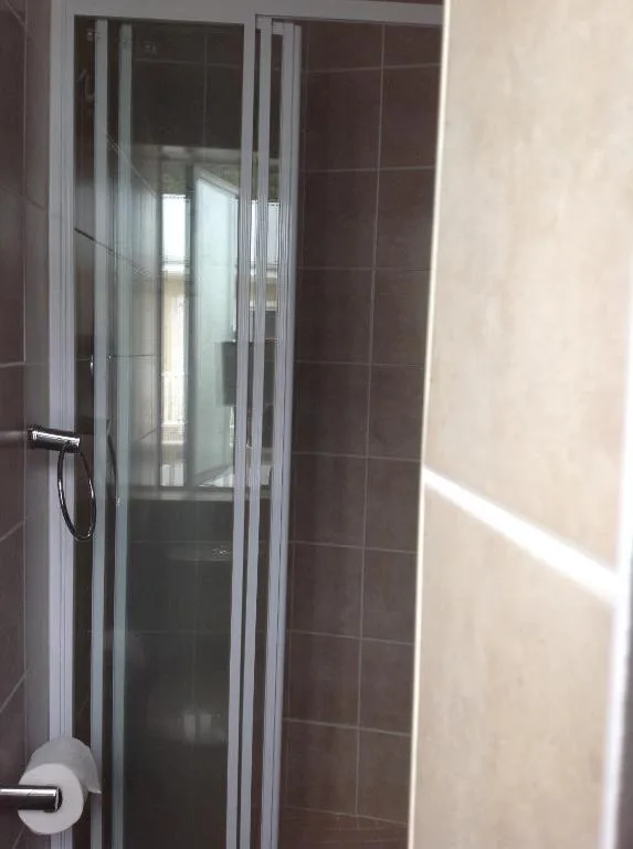 Modern enclosed shower cubicle with glass doors in tiled bathroom