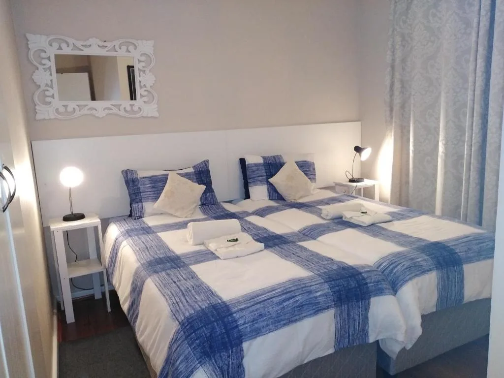 Twin beds with blue checked runner and white pillows in bright bedroom