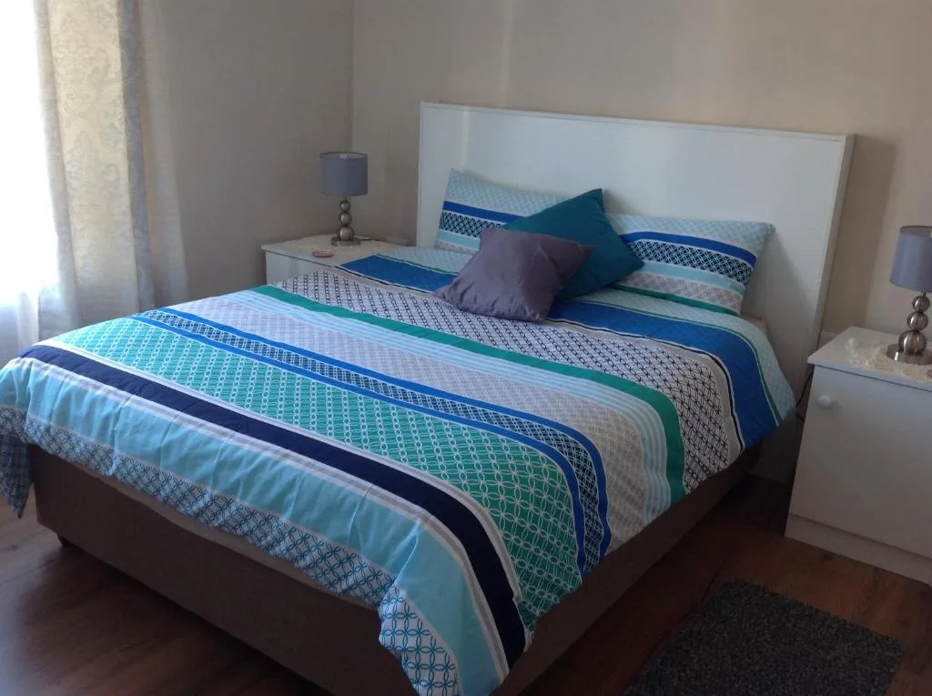 Bed with striped blue and green bedding and decorative pillows in bright room