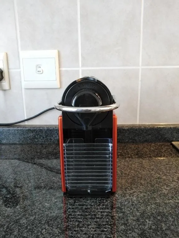 Red and black espresso machine on kitchen counter with white tiles