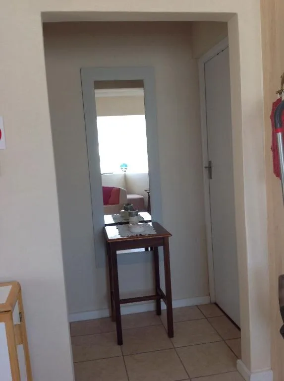 Hallway with small wooden table and mirror reflecting bright window light