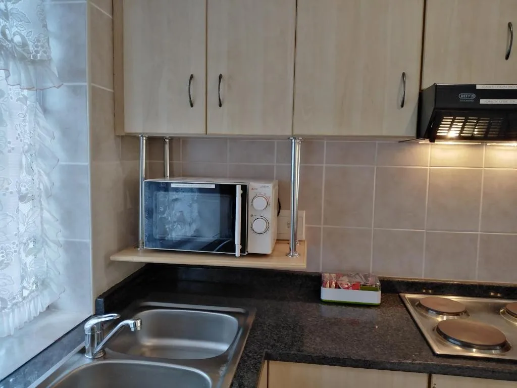 Compact kitchen with microwave, stove, sink, and cream cabinetry
