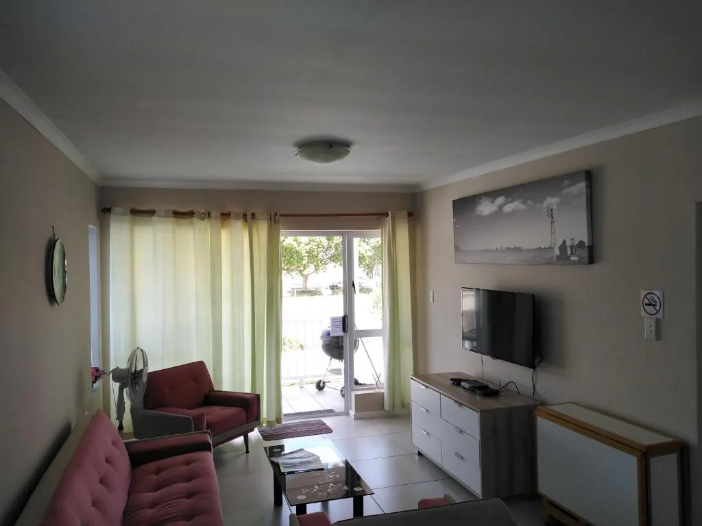 Bright living room with burgundy armchairs, TV, and glass doors to patio