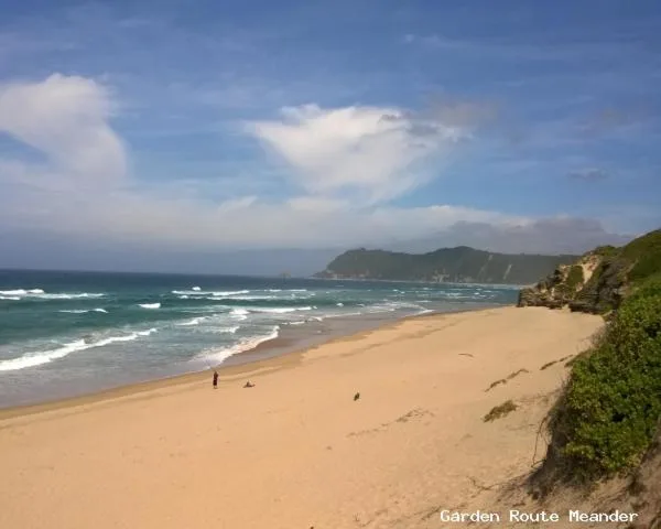 Sandy beach with turquoise waves and green coastal hills beyond