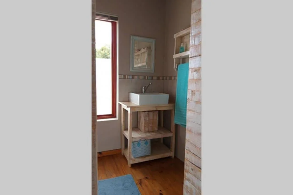 Compact bathroom with white basin, wooden vanity, and brick tiling