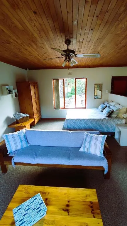 Spacious bedroom with wooden ceiling, sofa, and garden view doors
