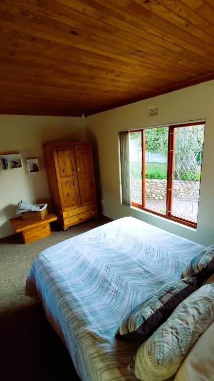Spacious bedroom with wooden ceiling, bed, wardrobe, and garden views