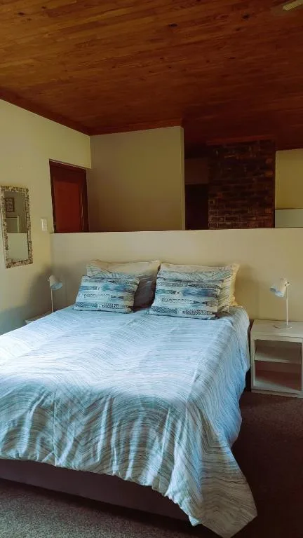 Bedroom with queen bed, blue striped bedding, wooden ceiling