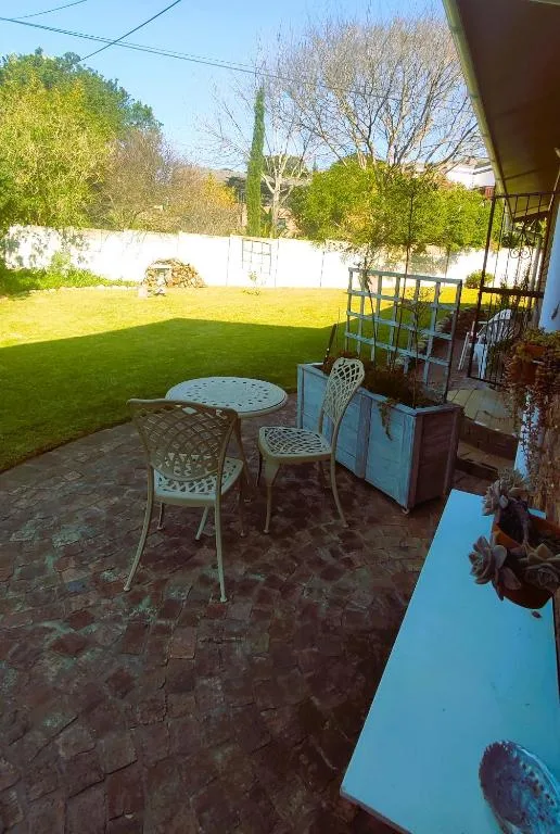 Patio seating area with metal chairs overlooking large green lawn
