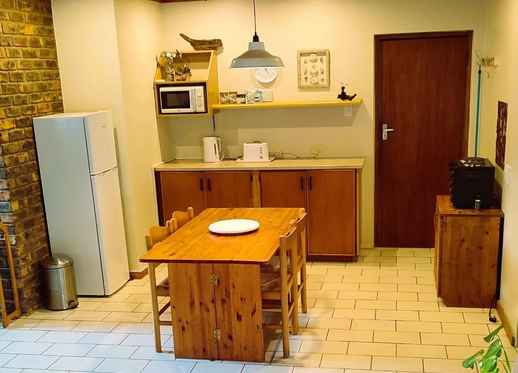 Kitchen with wooden dining table, refrigerator, microwave, and yellow shelving