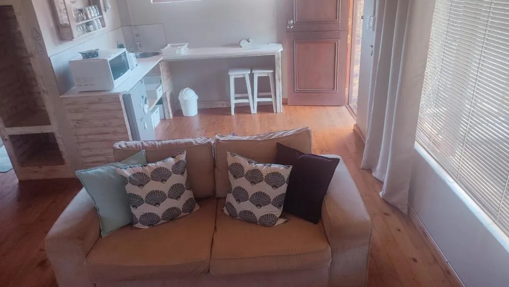 Spacious lounge with beige sofa and patterned cushions overlooking kitchen area