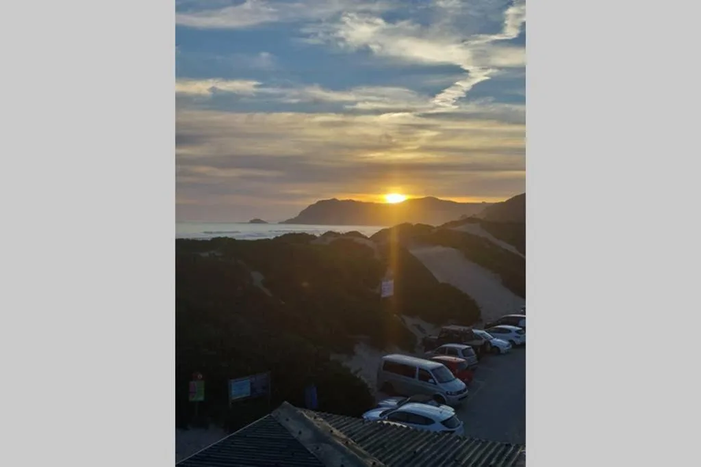 Sunset over coastal lagoon with mountains and parked cars below