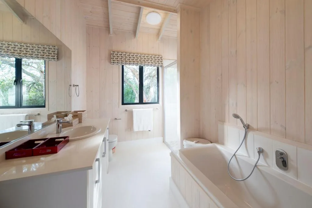 Modern bathroom with dual vanity, soaking tub, and natural wood finishes