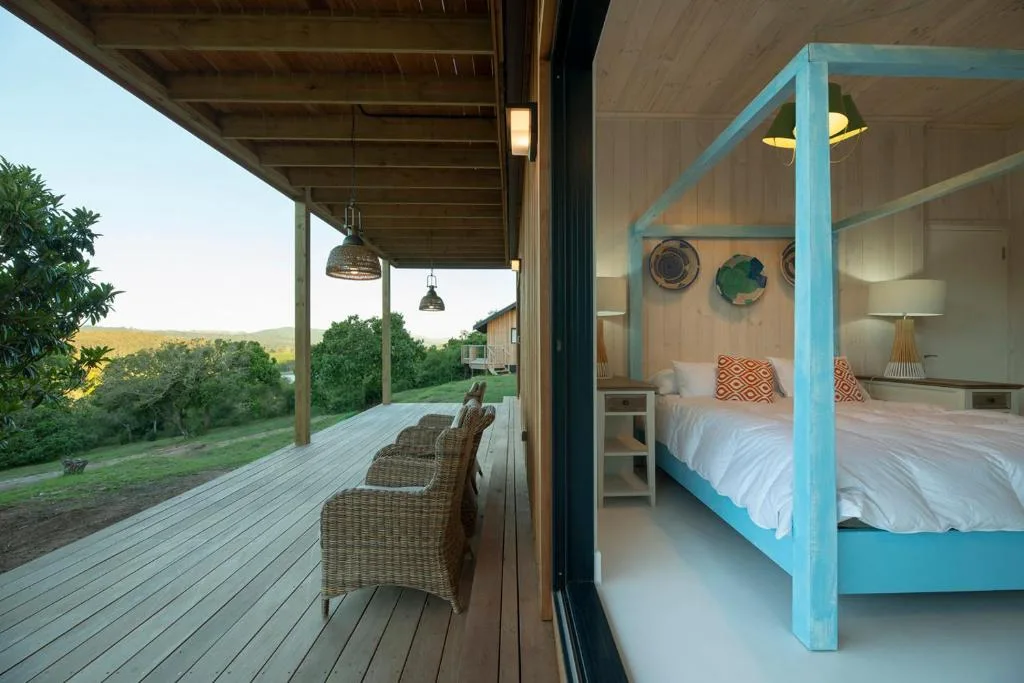 Bright bedroom with turquoise four-poster bed and deck views