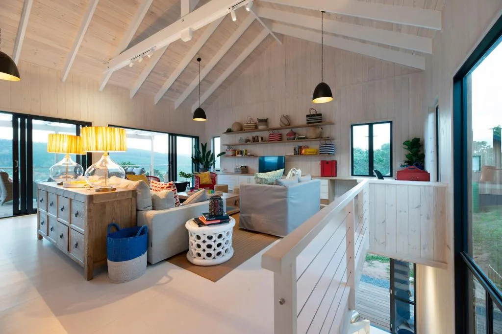 Modern open-plan lounge with vaulted ceiling, pendant lights, and expansive views