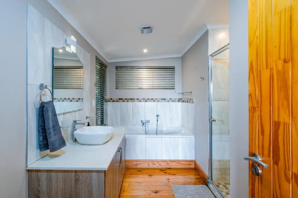 Modern bathroom with dual vanity, round sink, and spacious shower enclosure