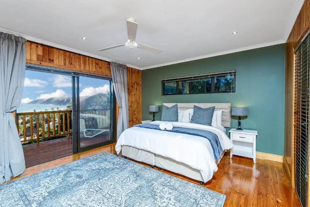 Spacious bedroom with mountain views, queen bed, turquoise accent wall, and deck access