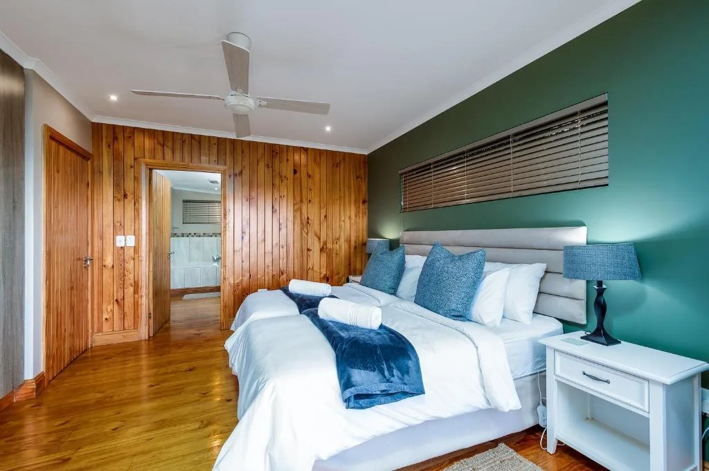 Spacious bedroom with king bed, teal accent wall, wooden cabinetry, ceiling fan
