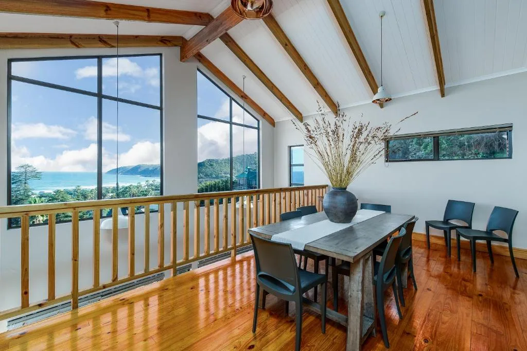 Spacious dining area with lagoon views through large windows and wooden beams