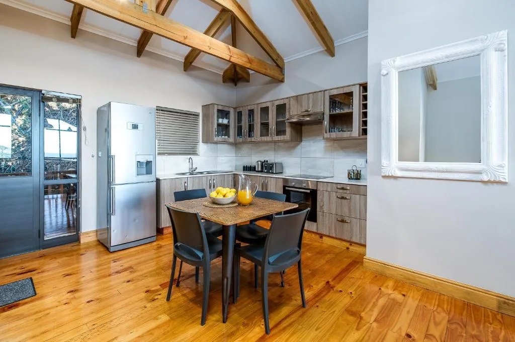 Open-plan kitchen with dining table, modern appliances, and exposed wooden beams