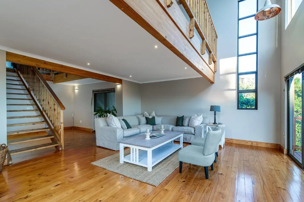 Spacious living room with white sectional sofa, wooden floors, and large windows